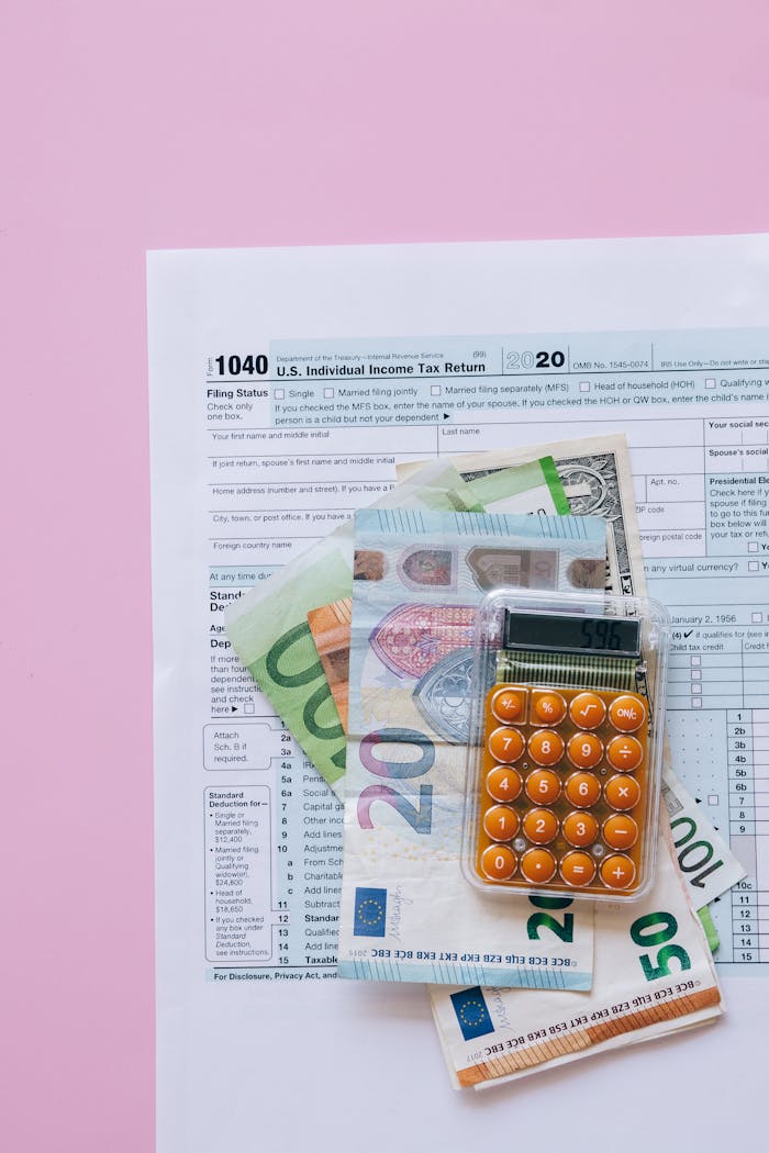about-01 A vibrant flat lay of a calculator, euro banknotes, and US tax forms on a pink background.
